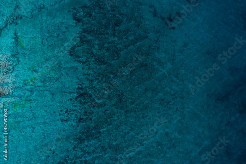 Top down view of a rocky sea texture with clear blue water