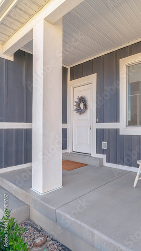 Vertical frame White porch chairs against window and front door of home with gray exterior wall