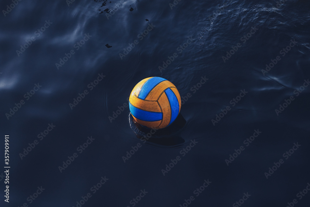 Blue and yellow volleyball ball in the water. Water polo sport background. Lost the ball.