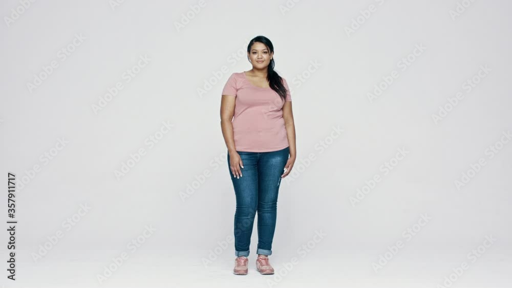Full length of a woman in tshirt and jeans standing over white background. Plus size woman looking at camera.
Full length of a woman in tshirt and jeans standing over white background. Plus size woman looking at camera.