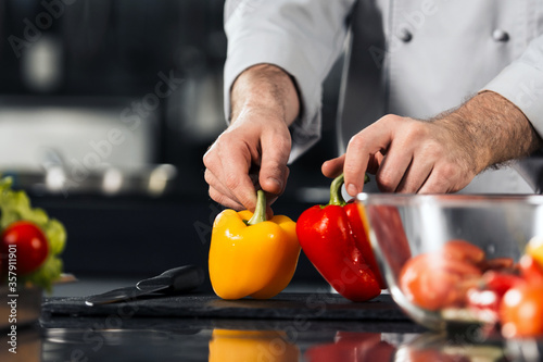 Healthy food at kitchen table. Closeup chef hands with yellow and red pepper.