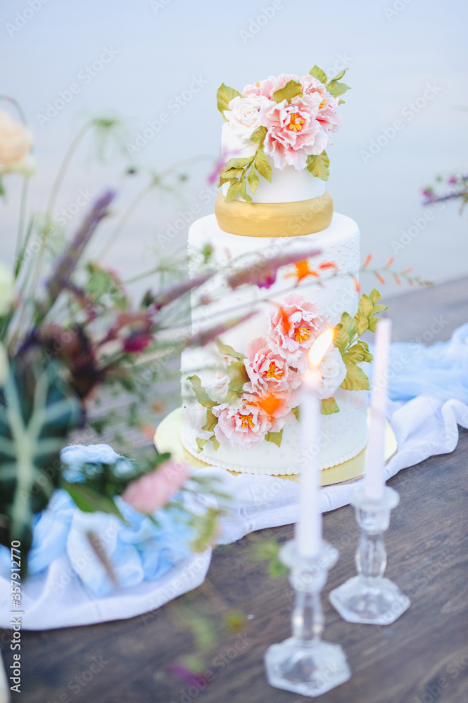 Beautiful wedding cake on a wooden table on the nature.
Stylish wedding flower decor. wedding flowers on the table