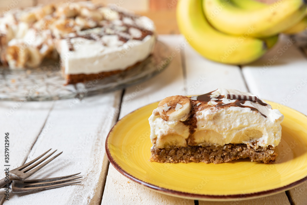 frisch gebackene Torte mit Bananen, Sahne, Schokosoße, Karamellsoße und Haselnussboden auf Tisch aus Holz in der Küche zum Kaffeetrinken frisch gebackene Torte mit Bananen, Sahne, Schokosoße, Karamellsoße und Haselnussboden auf Tisch aus Holz in der Küche zum Kaffeetrinken