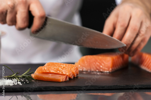 Chef hands cutting fish fillet. Closeup male hands slicing salmon.