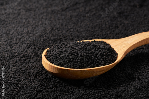 wooden spoon filled with black caraway seeds. food background.