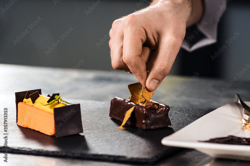 © stockbusters - Chef hands decorate dessert. Closeup hands decorate cake with chocolate.