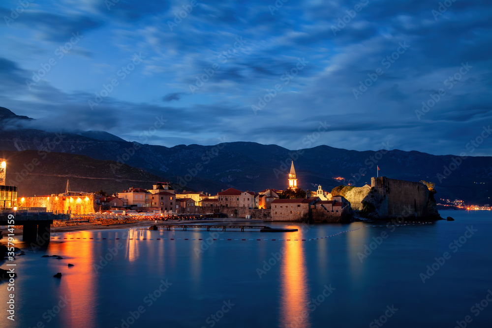 Budva city old town houses architecture history Montenegro tourist landmark summer vacation travel destination. Evening night time long exposure sky landscape panorama. Adriatic sea and mountains.