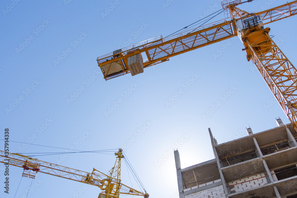 Construction site with cranes on a background of blue sky. The concept of the construction of monolithic high-rise buildings using modern technologies