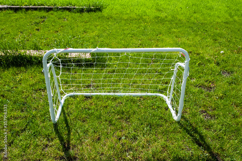 Mini football goal on the green grass on a plot near the house. Family play Mini football goal on the green grass on a plot near the house. Family play
