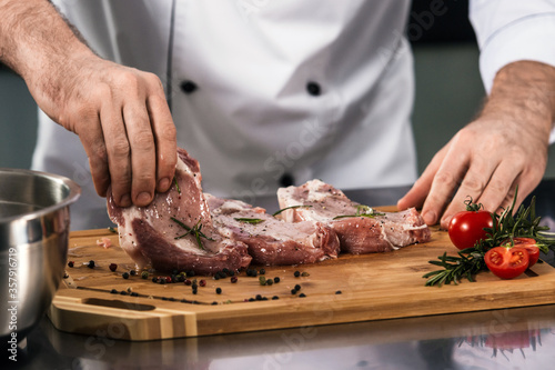 Chef hands prepare beef at kitchen restaurant. Closeup raw beefsteak at planked.