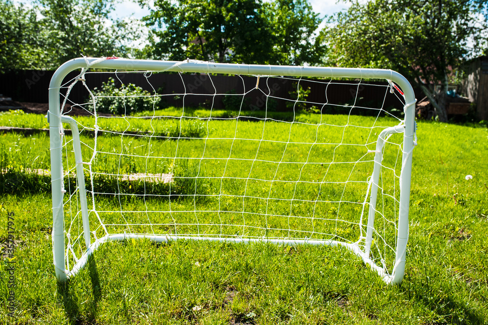 Mini football goal on the green grass on a plot near the house. Family play Mini football goal on the green grass on a plot near the house. Family play