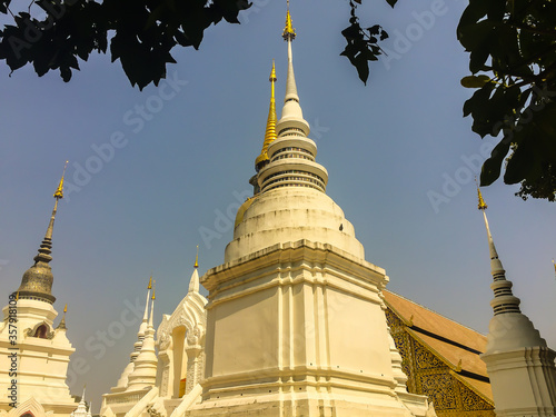 Beautiful golden and white pagodas in Sri Lankan style at Wat Suan Dok (flower garden temple) with blue sky background. Wat Suan Dok, also known as Wat Buppharam, built in 1370, Chiang Mai, Thailand. photo