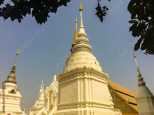 Beautiful golden and white pagodas in Sri Lankan style at Wat Suan Dok (flower garden temple) with blue sky background. Wat Suan Dok, also known as Wat Buppharam, built in 1370, Chiang Mai, Thailand. photo
