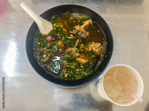 Hot and spicy soup with pork ribs, or Tom Saeb Kraduk Moo, Thai style food. Tom yum pork cartilage soup with chili and onion leaf.