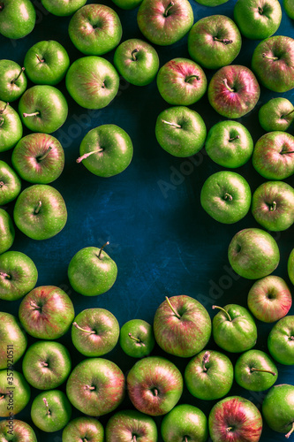 Fresh green organic apples vibrant color overhead arrangement on blue background studio shot
