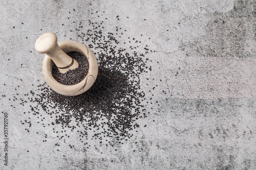 Black sesame crushed in pestle arrangement on gray rustic background overhead studio shot