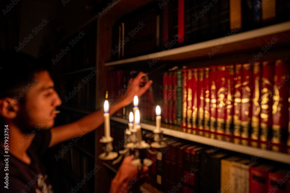 Boy holding book from the library in the dark with candles to light his way Boy holding book from the library in the dark with candles to light his way