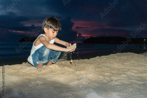 Quadro su tela A boy playing sand in twilight on Kata beach Phuket Thailand..