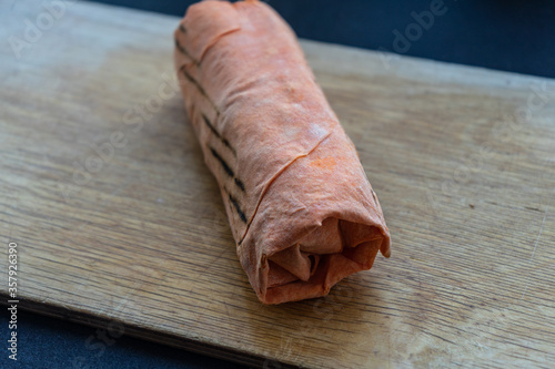 Shawarma  fresh roll of lavash, chicken beef shawarma falafel, grilled meat, mushrooms, cheese. Traditional Middle Eastern snack. On wooden background. photo