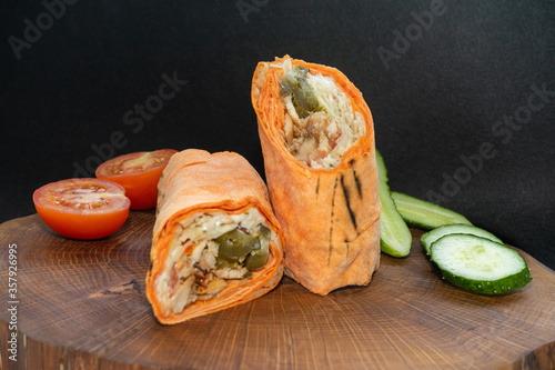 Shawarma  fresh roll of lavash, chicken beef shawarma falafel, grilled meat, mushrooms, cheese. Traditional Middle Eastern snack. On wooden background. photo