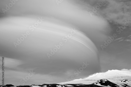 interesting shaped clouds, snowy volcanic mountain in a sunny day in black and white