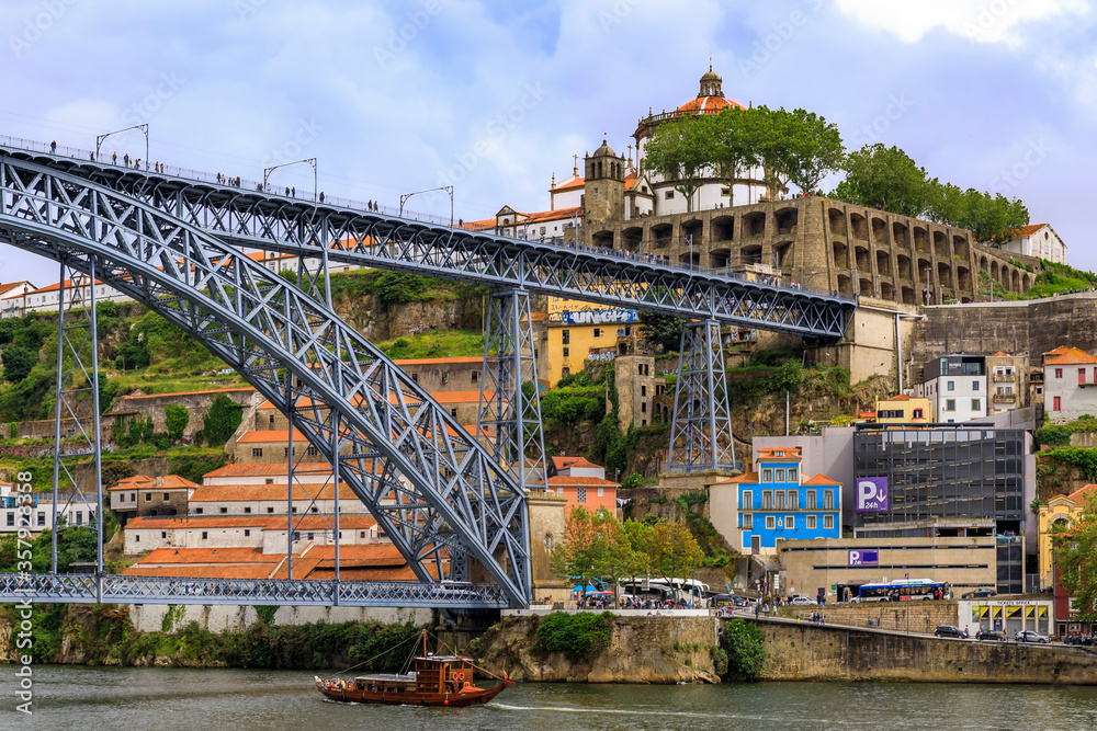 View across Douro and Dom Luis I bridge onto Vila Nova de Gaia and traditional tourist rabelo boats in Porto, Portugal