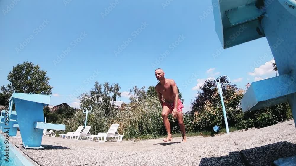 Fit athletic man head jump into the refreshing swimming pool, slow motion Fit athletic man head jump into the refreshing swimming pool, slow motion
