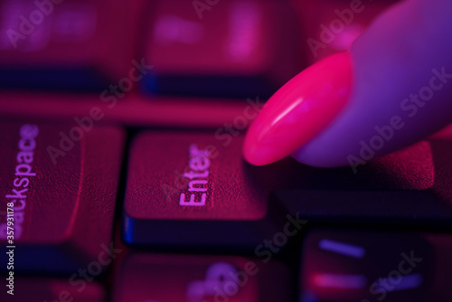 Foto Female finger pressing enter button of keyboard.