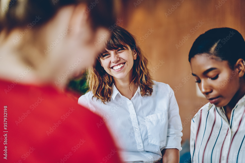 Curly woman with wide smile looking at colleague in multiracial group of people Curly woman with wide smile looking at colleague in multiracial group of people