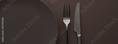Empty plate and cutlery as mockup set on dark brown background, top tableware for chef table decor and menu branding