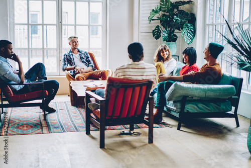 Group of delighted multiethnic friends chatting at home photo