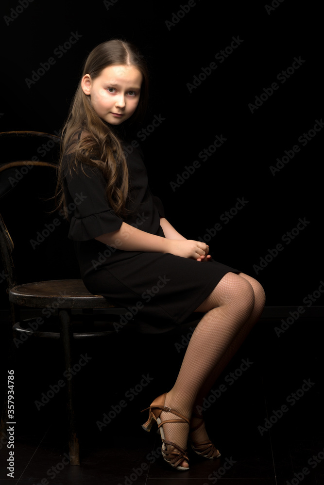 Portrait of a little girl sitting on an old Viennese chair, black background. Portrait of a little girl sitting on an old Viennese chair, black background.
