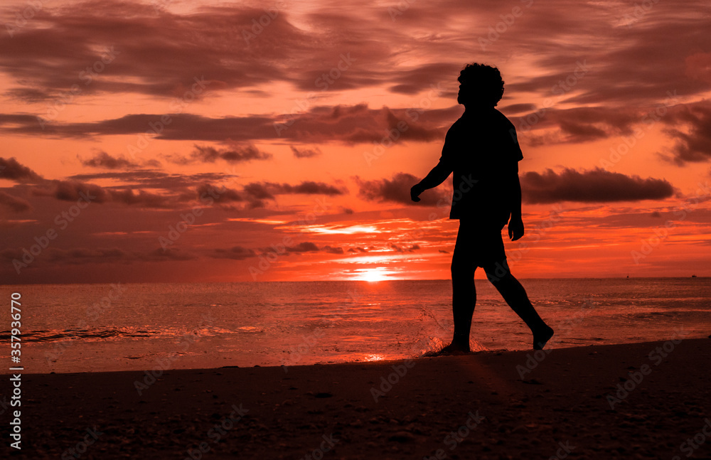 Man walking in the beach at sunset