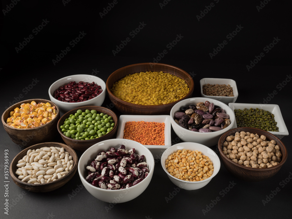 Organic legumes. Black background. Different varieties of peas, beans and lentils.