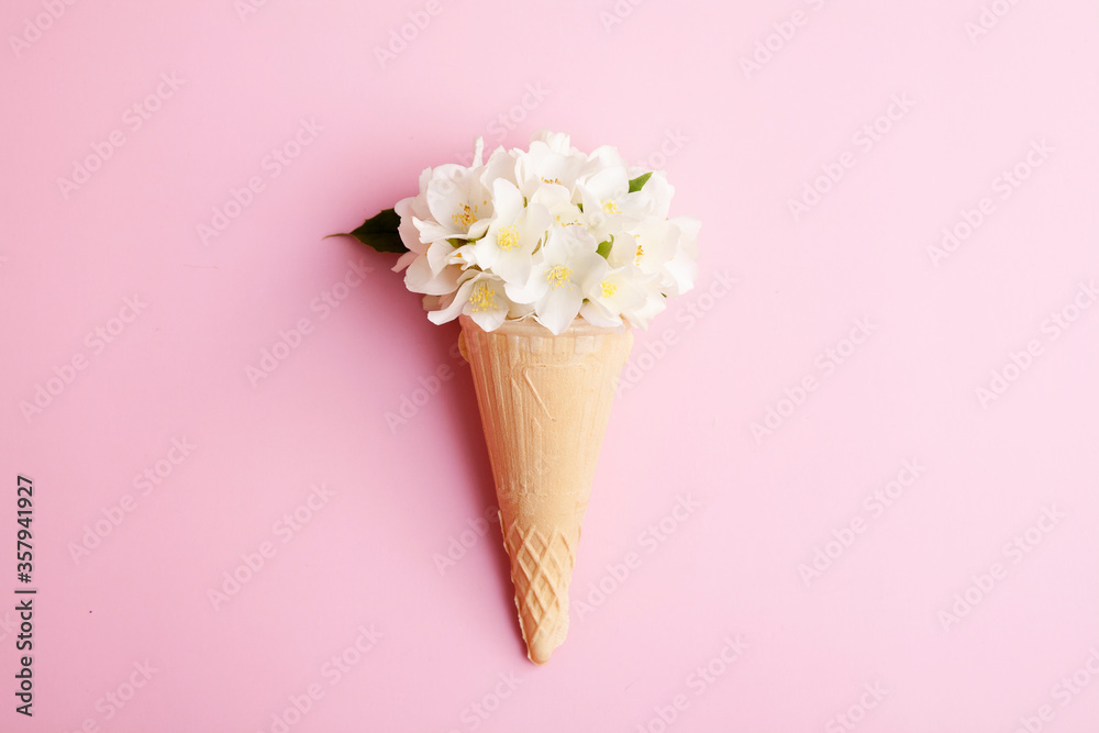 Fototapeta Waffle ice cream cone with jasmine flowers on a pink background. Summer concept