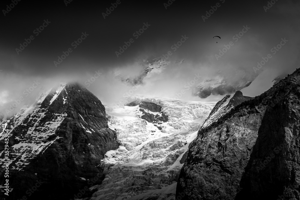 Paraglider in front of a glacier in black and white