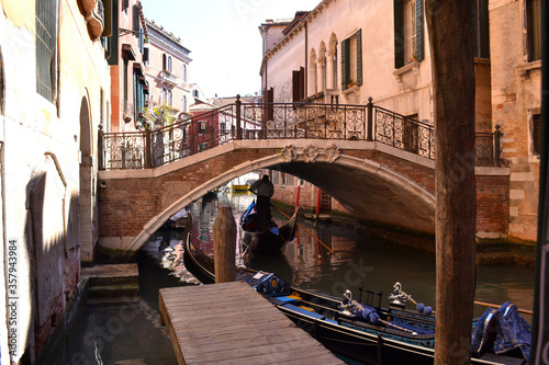 A beautiful Venetian canal with a bridge, gondolas and old houses on a Sunny day. © Svetlana
