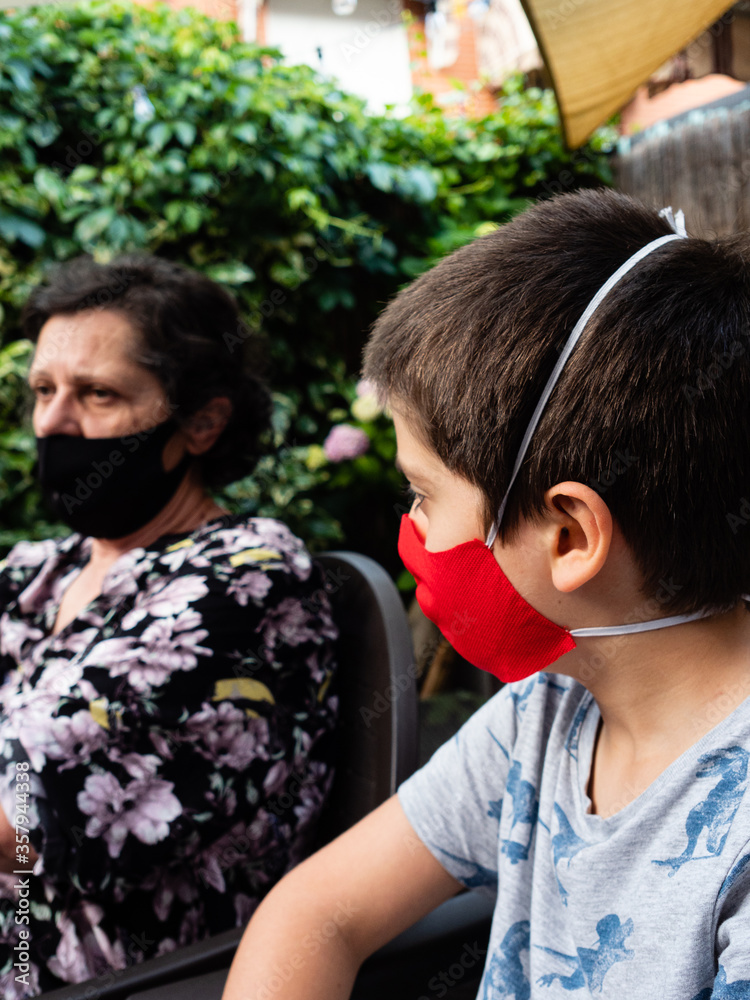 Caucasian boy with red homemade mask, watches his grandmother at home Caucasian boy with red homemade mask, watches his grandmother at home
