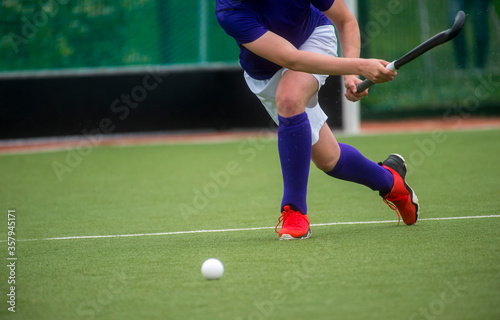 Field Hockey player, forcefully passing the ball. Team sport concept