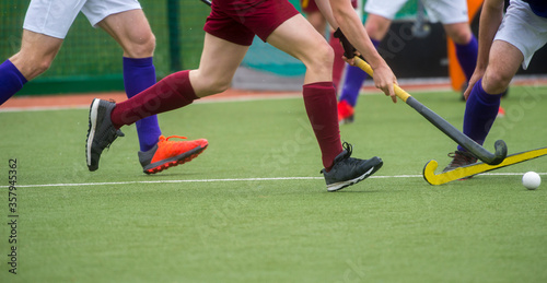 Three field hockey player, fighting for the ball on the midfield during an intense match on artificial grass