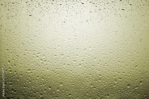 Drops of rain on a window glass with very diffuse landscape yellow color