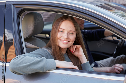 Adorable smiling lady sitting with her arm outside the car