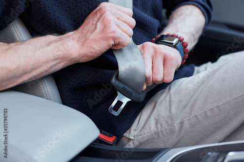 Male driver buckling up in his modern auto