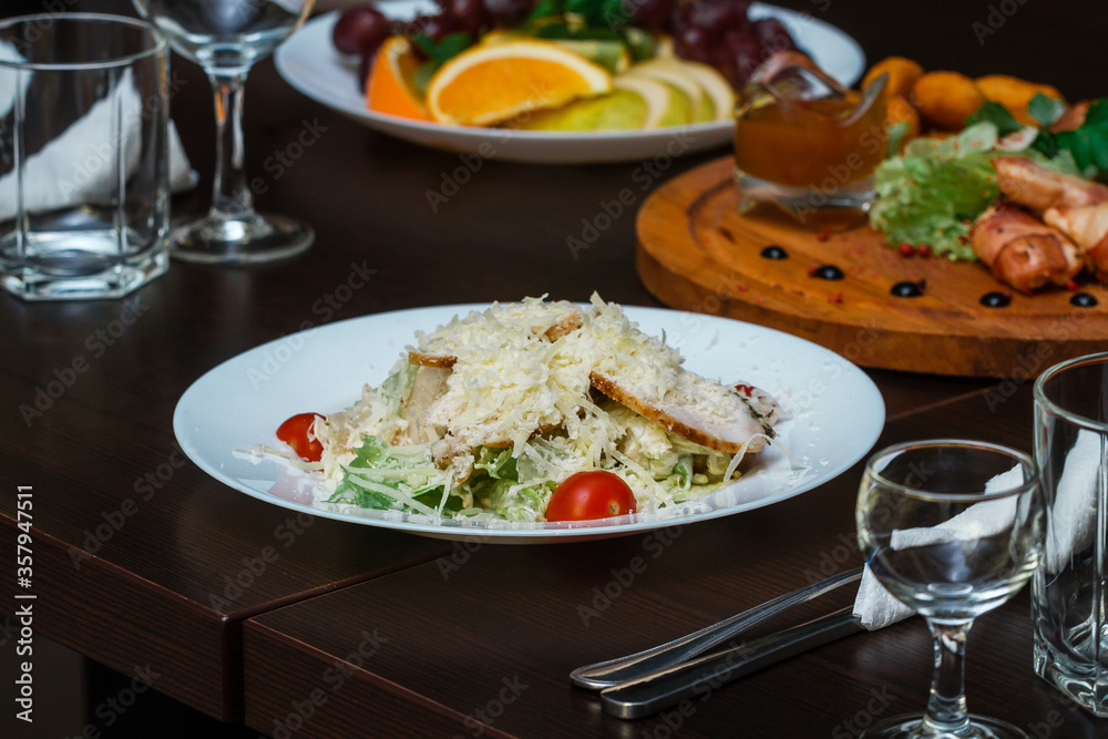 Caesar salad in a white plate on a table in a restaurant