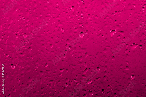 Water drops on glass with vivid medium contrast reddish pink color