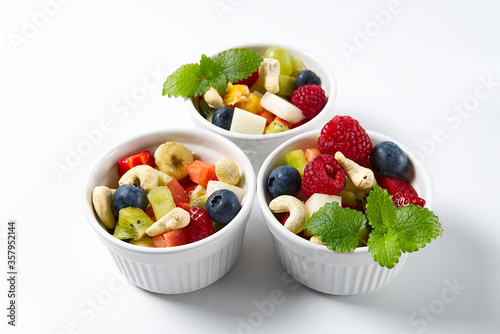 Fresh fruit salad on white bowl. Mixed fruit in white bowl healthy food style. Useful fruit salad of fresh fruits and berries on pink background. three bowls with fruit salad