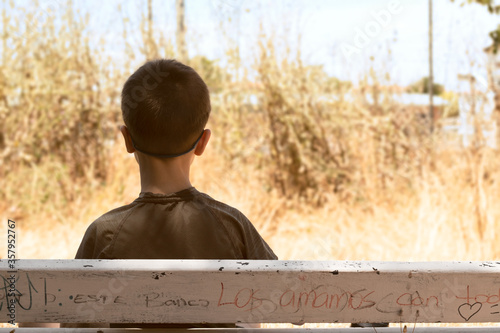 Niño sentado en banco de espaldas