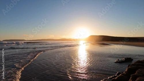 Sunset view of Drakes Beach, the sunlight reflected on the water surface and the wet sand, Point Reyes National Shoreline, California