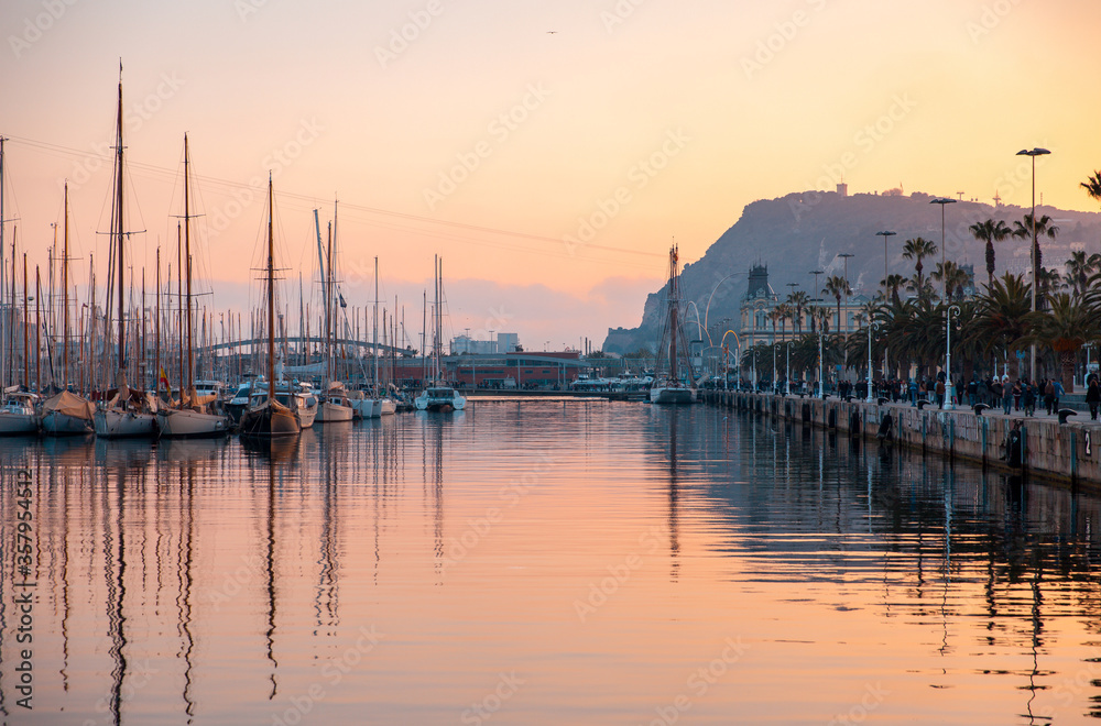 Sunset over the marina in Barcelona Spain with water reflections and view of Mont Juic