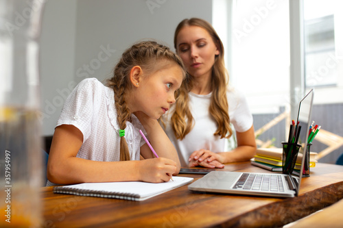 Adorable little girl studying with mother at home
